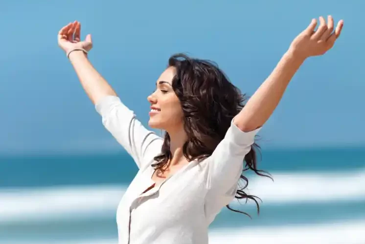 a woman with her arms raised on a beach